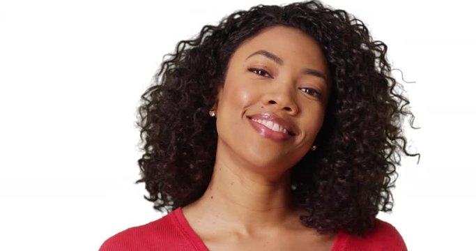 Close-up of pretty African woman with curly hair laughing at camera in studio