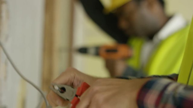  Construction workers on a building site drilling & checking wiring