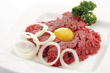 Tartare, egg yolk, raw onion rings and parsley