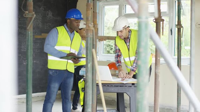  Builders working at construction site with architects or engineers overseeing