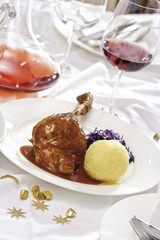 Goose-leg, red cabbage, potato dumpling on a festively decorated table
