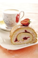 Rolled spongecake with strawberries, cup of coffee in background