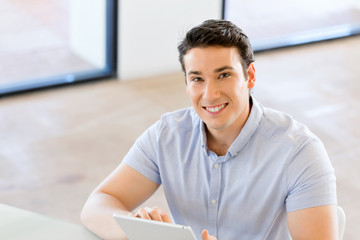 Young handsome businessman using his touchpad sitting in office