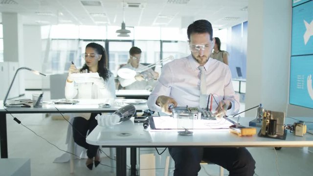  Electronics engineers working in lab with man building circuit board