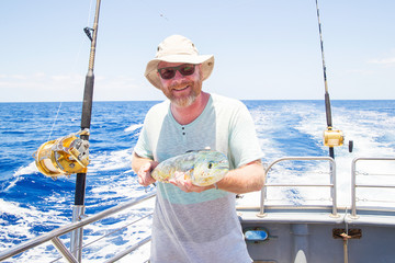 Man holding fresh caught Mahi Mahi on ocean boat