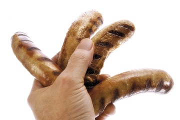 Hand holding four grilled sausages