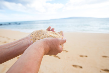 hands holding and dropping sand at a tropical ocean beach