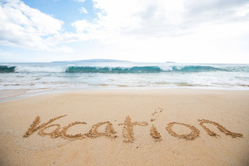 Fototapeta na wymiar The word vacation written in sand at a tropical island beach