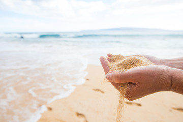 hands holding and dropping sand at a tropical ocean beach