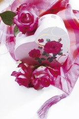 Heart-shaped gift box with roses on a silky cloth
