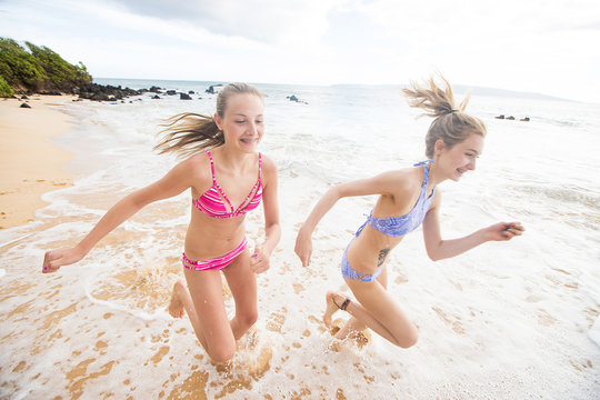 Two girls running on ocean beach