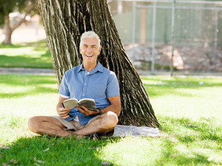 Senior man sittingin park while reading book