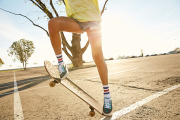 Girl doing a skateboard trick skateboarding on a parking in the sunset in Sochi
