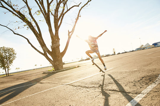 Girl doing a skateboard trick skateboarding on a parking in the sunset in Sochi