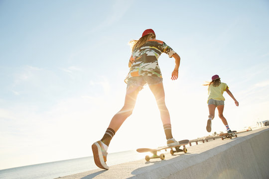 Girls skateboarding on a bank of the sea in the sunset in Sochi