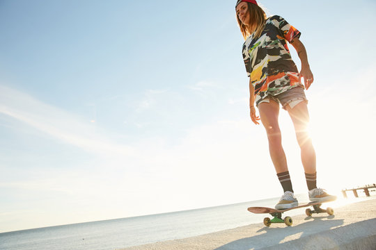 Girl skateboarding on a bank of the sea in the sunset in Sochi