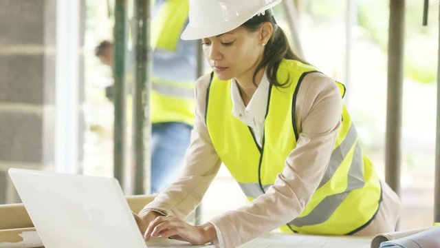  Architect with laptop at construction site discussing plans with foreman
