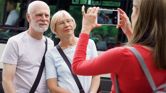 Daughter taking photo of her senior parents on vacation trip in Paris. Happy family enjoying vacation. Cars abd busses passing by