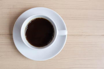 White cup of hot coffee on wooden table with copy space. Beginning the new working day in the morning with coffee. 
