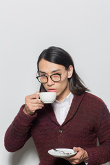 Asian young man drinking hot tea or coffee from white cup