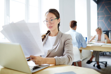 Executive businesswoman reading important papers by her workplace