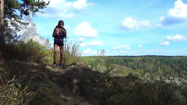 Young woman with a backpack goes on mountain trail. 
