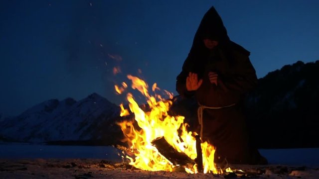 monk meditates next to the campfire
