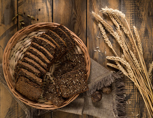 Fototapeta na wymiar sliced rye bread in a wicker tray and spikelets on wooden surface