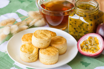 Homemade plain scones serve with homemade passion fruit jam. Scones is traditional English pastry for afternoon tea or coffee break. Delicious plain scones ready to served on wood table.