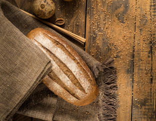 a loaf of bread on a cloth napkin on a wooden surface, top view