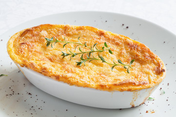 pastitsio in oval bowl decorated with thyme and sumac