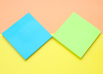 blue and light green sticks note on yellow with a coral background.Flat.Paper for writing ideas.Memo