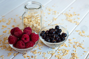 Raspberries and blueberries in a plate on a white background. Summer seasonal berries for a diet