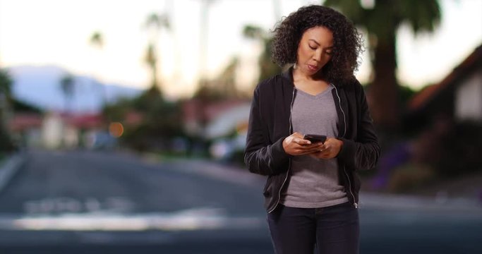 Cute black woman enters on screen, answers text message and walks off