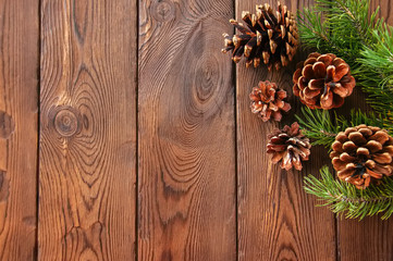 Christmas backdrop. Fir tree branches and cones on a wooden background.