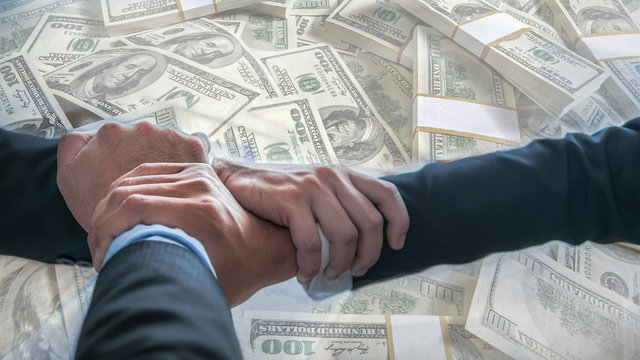 The double exposure image of financial and dollar trading business concept. The businessmen put hands together with the contract and overlay with dollars in the theme of business cooperation.