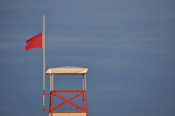 Tower of a marine lifeguard with a red flag hanging out. Swimming prohibited.