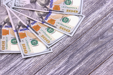 American hundred dollar bills on gray wooden background.