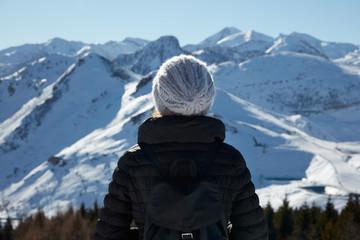 Fototapeta na wymiar Woman with wool hat looking at mountains with snow in a sunny winter day