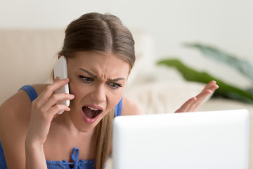 Angry dissatisfied young woman calling customer support or mobile banking, displeased client...