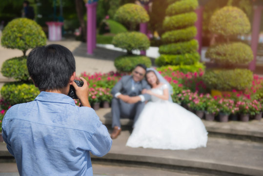 wedding photographer takes pictures of the bride and groom in park, the photographer in action.