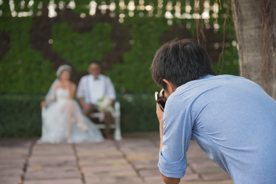 wedding photographer takes pictures of the bride and groom in park, the photographer in action.