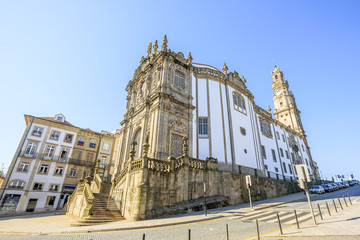 Fototapeta na wymiar Side view of majestic baroque Church of Clerigos or Igreja dos Clerigos, in Portuguese, and iconic Clerigos Tower, one of the landmarks and symbols of Oporto city in Portugal. Sunny day with blue sky.