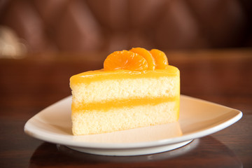 Orange cake on plate with blur brown background