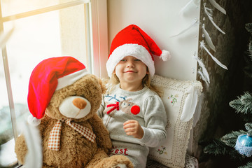 happy child girl sitting back in the winter window Christmas
