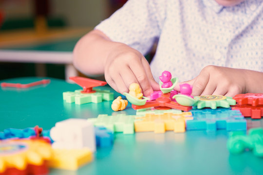 Little boy's hands playing with colorful plastic bricks at the table. Kids having fun and building out of bright constructor bricks. Early learning. Developing toys