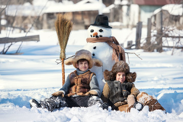 Children shape the snowman in the backyard of the house