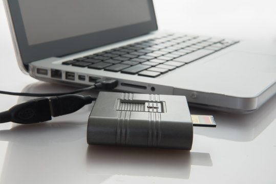 SD card and card reader conected to laptop close-up.