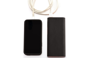 Smartphone charging with power bank on white background.