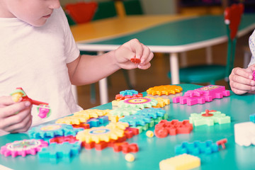 Little boys playing with colorful plastic bricks at the table. Kids having fun and building out of bright constructor bricks. Early learning. Developing toys